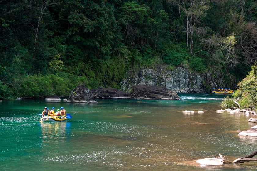white water rafters paddling through quiet section of Tully Gorge, North Queensland